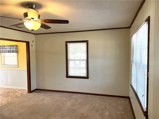 empty room featuring ceiling fan, light colored carpet, and ornamental molding