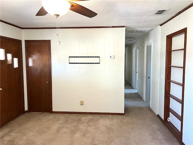 carpeted spare room with ceiling fan, ornamental molding, and a textured ceiling