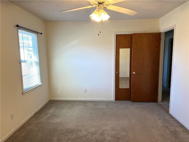 carpeted empty room with a textured ceiling and ceiling fan