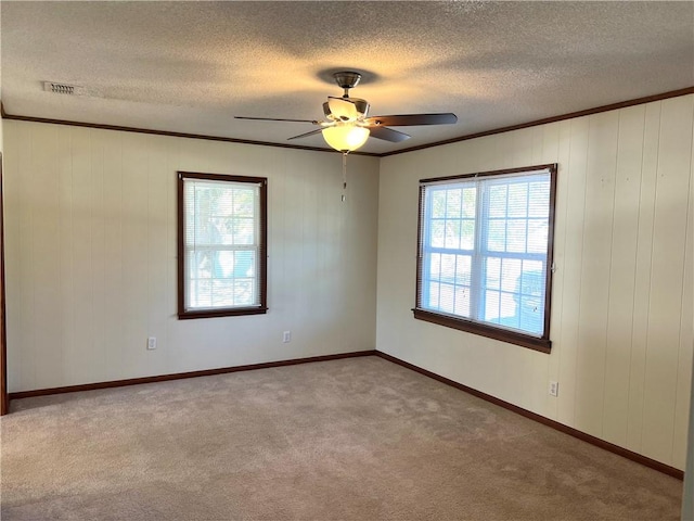 carpeted spare room featuring ceiling fan, a healthy amount of sunlight, and crown molding