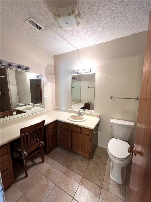 bathroom with tile patterned flooring, vanity, toilet, and a textured ceiling