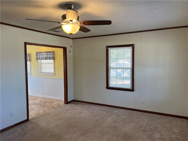 empty room with carpet flooring, ceiling fan, ornamental molding, and a textured ceiling