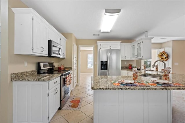 kitchen with a sink, white cabinets, light tile patterned floors, and stainless steel appliances