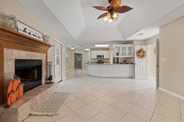 unfurnished living room featuring ceiling fan, baseboards, vaulted ceiling, light tile patterned floors, and a tile fireplace