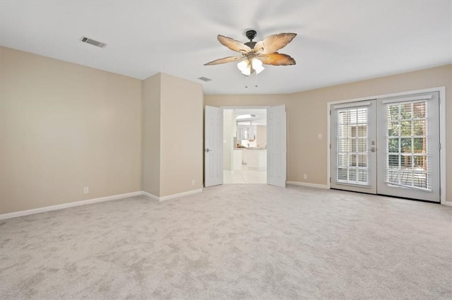 carpeted spare room with visible vents, baseboards, a ceiling fan, and french doors