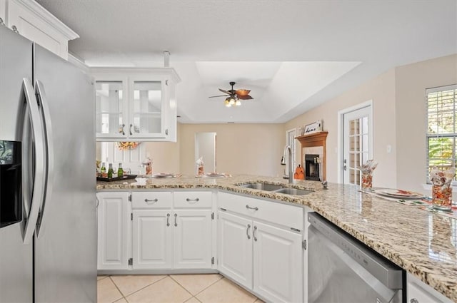 kitchen featuring light stone counters, light tile patterned floors, appliances with stainless steel finishes, white cabinets, and a sink