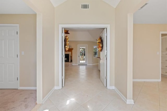 corridor with light tile patterned floors, visible vents, baseboards, and lofted ceiling