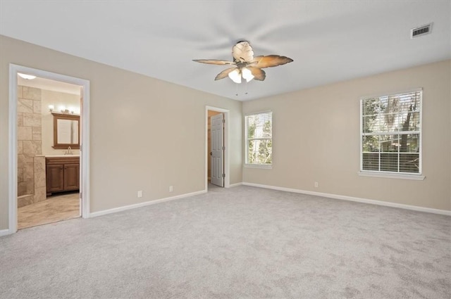 unfurnished bedroom with light colored carpet, visible vents, ensuite bathroom, and baseboards