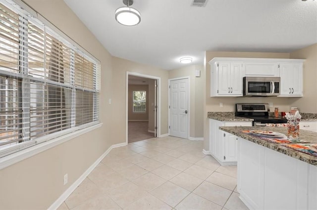 kitchen featuring light stone countertops, baseboards, light tile patterned flooring, white cabinets, and appliances with stainless steel finishes