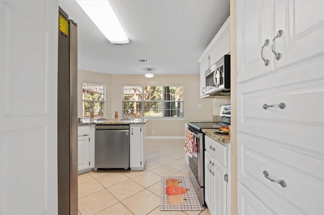 kitchen featuring visible vents, light stone countertops, light tile patterned floors, appliances with stainless steel finishes, and white cabinetry