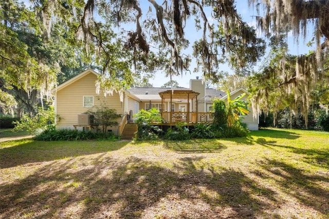 back of property with a wooden deck, a lawn, and a chimney