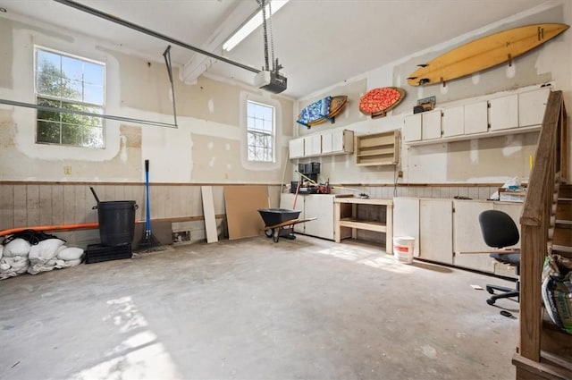 garage with a workshop area, wood walls, and wainscoting