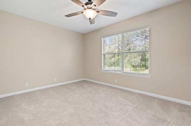 empty room featuring light colored carpet, baseboards, and ceiling fan