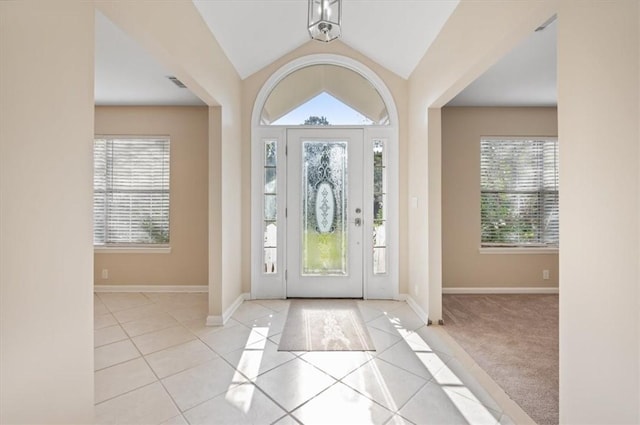 foyer entrance with tile patterned flooring, lofted ceiling, baseboards, and visible vents