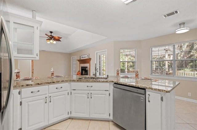 kitchen featuring light stone countertops, light tile patterned floors, white cabinets, stainless steel appliances, and a sink