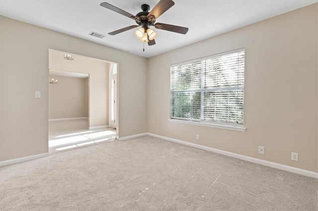 empty room with carpet flooring, ceiling fan with notable chandelier, visible vents, and baseboards