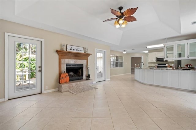 unfurnished living room featuring light tile patterned floors, a tray ceiling, and a tiled fireplace