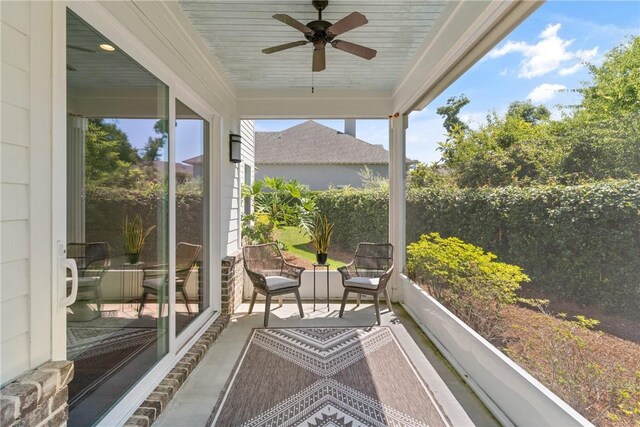 1040 Sinclair Pointe, Saint Simons Island, GA 31522 - rear view of property featuring stone siding, a ceiling fan, a sunroom, and fence