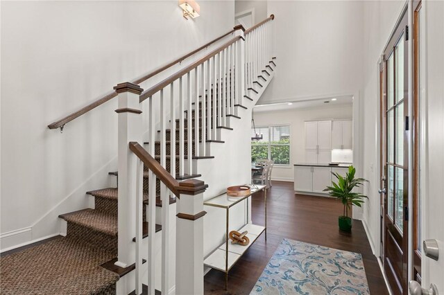 1040 Sinclair Pointe, Saint Simons Island, GA 31522 - stairway featuring a high ceiling, baseboards, and wood finished floors