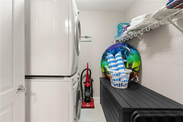 clothes washing area featuring baseboards, laundry area, and stacked washing maching and dryer