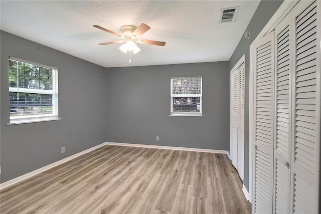 124 Ryals Rd, Brunswick, GA 31523 - unfurnished bedroom with light wood-type flooring, two closets, a ceiling fan, and a textured ceiling