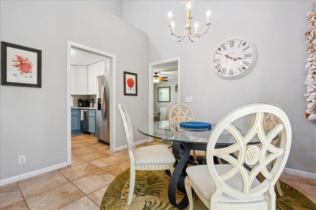 dining space with a chandelier, baseboards, a ceiling fan, light tile patterned floors, and a towering ceiling