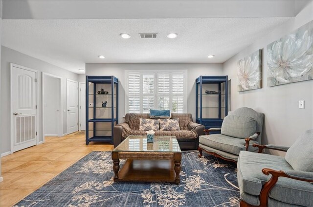 living area with a textured ceiling, light tile patterned floors, baseboards, and recessed lighting