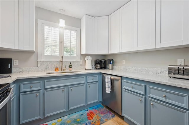kitchen with stainless steel appliances, a sink, and blue cabinetry