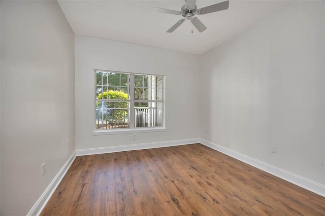 empty room with dark wood-style floors, baseboards, and ceiling fan
