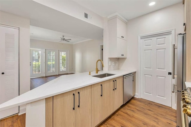 kitchen with visible vents, a sink, light wood-type flooring, appliances with stainless steel finishes, and a peninsula
