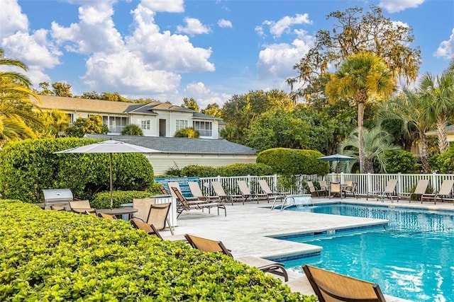 community pool with fence, a patio, and a grill