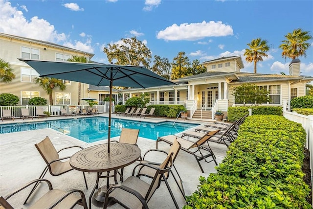 pool with french doors, fence, and a patio