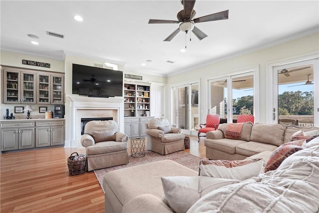 living room with ceiling fan, light wood-type flooring, and ornamental molding