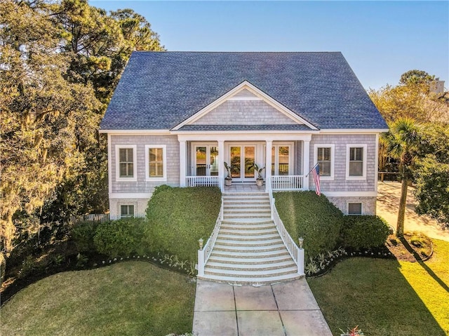 view of front of house featuring french doors, covered porch, and a front yard