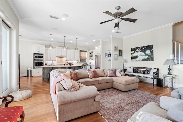 living room featuring ceiling fan, light wood-type flooring, and ornamental molding