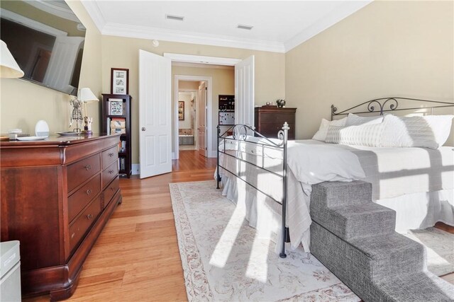 bedroom with light wood-type flooring and crown molding