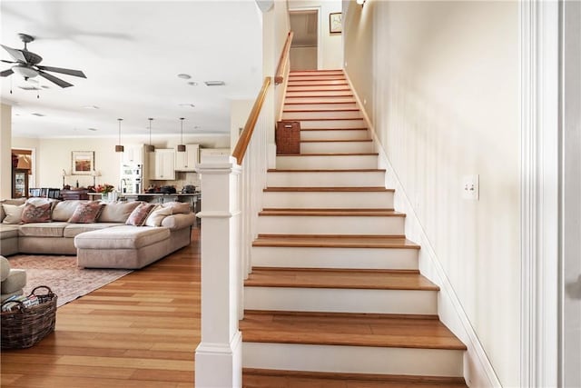 staircase featuring wood-type flooring and ceiling fan