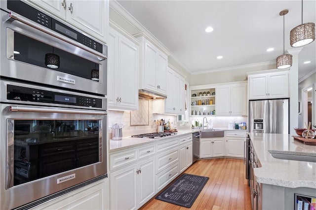 kitchen with stainless steel appliances, light stone counters, decorative light fixtures, white cabinets, and light wood-type flooring