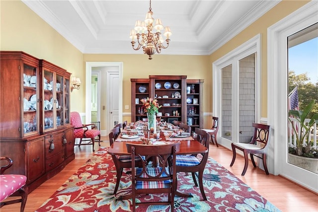 dining space featuring an inviting chandelier, a tray ceiling, and light hardwood / wood-style flooring