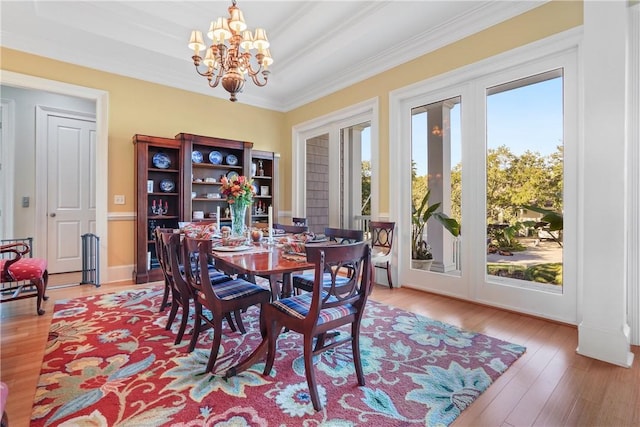 dining space featuring hardwood / wood-style flooring, a notable chandelier, a healthy amount of sunlight, and crown molding