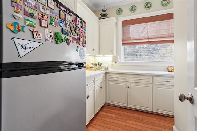 kitchen with white cabinetry, stainless steel fridge, ornamental molding, and light wood-type flooring