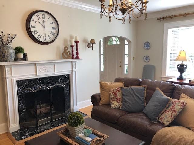 living area with arched walkways, a notable chandelier, ornamental molding, and a fireplace