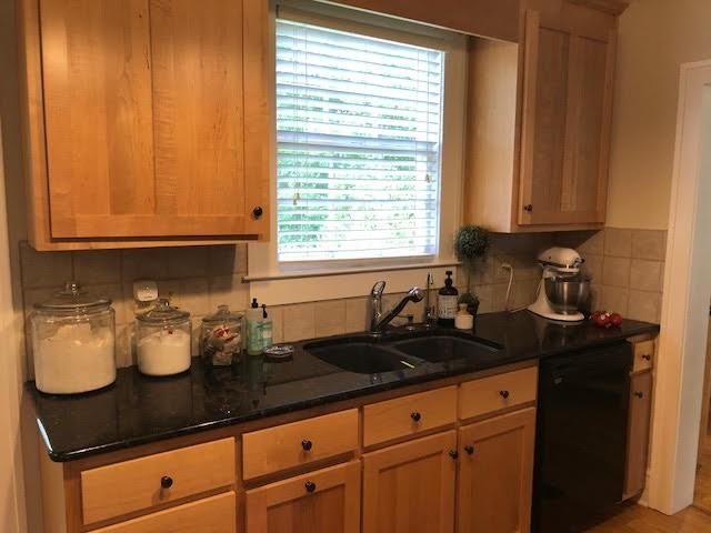 kitchen featuring black dishwasher, tasteful backsplash, and a sink