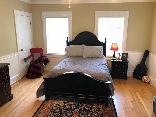 bedroom featuring crown molding, wood finished floors, and wainscoting