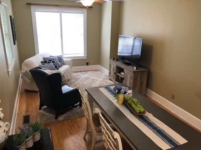 living area with light wood-style floors, baseboards, and ceiling fan