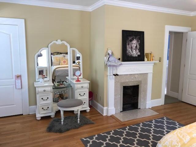 interior space with a fireplace, wood finished floors, baseboards, and ornamental molding