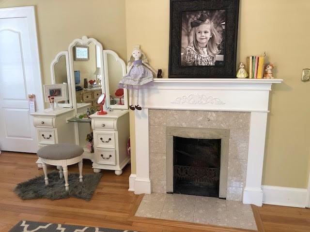 interior details featuring baseboards, wood finished floors, and a tile fireplace