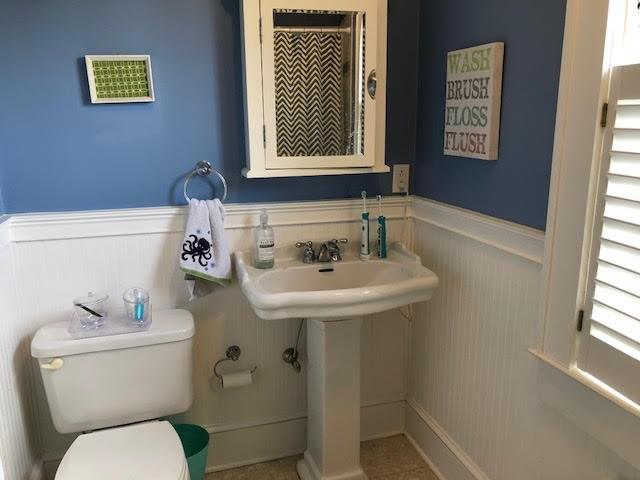 half bath with visible vents, toilet, and wainscoting