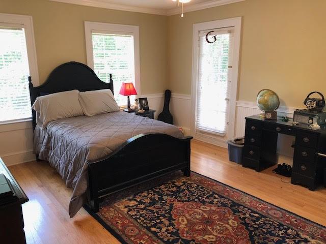 bedroom featuring wainscoting, wood finished floors, and multiple windows