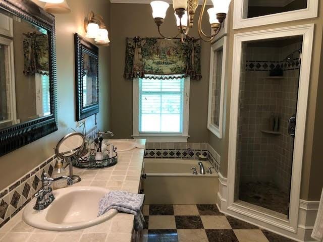 full bath featuring a bath, a chandelier, a shower stall, and a sink